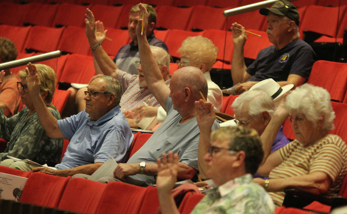 Election judges raise their hands to be sworn in during training Thursday at Hatheway Auditorium at Lewis and Clark Community College. It was the last of seven training sessions before the June 28 primary election.
