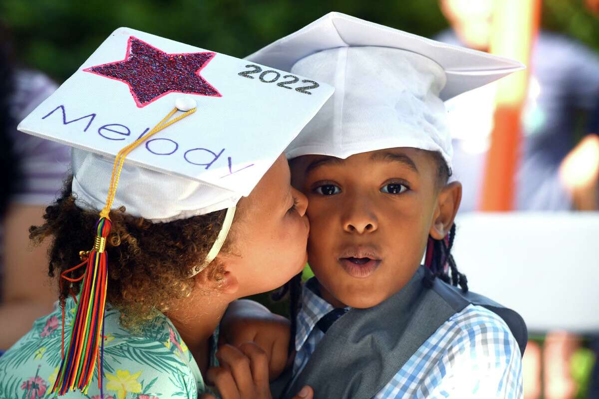 Johnny Hooper gets a kiss on the cheek from classmate Melody Robinson during a graduation ceremony for Armstrong Court Preschool students held at Byram Park, in Greenwich, Conn. June 24, 2022.