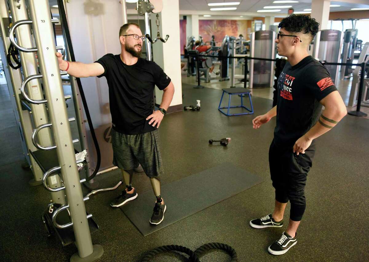 Stamford resident Rome Leykin, left, works out with his trainer, Tarik Elbouhali, at LA Fitness in Stamford, Conn. Thursday, June 23, 2022. Leykin lost both of his legs above the knee in a subway accident in 2018 and will be participating in two races this weekend, one in Wallingford with his trainer, and the other in New York City.