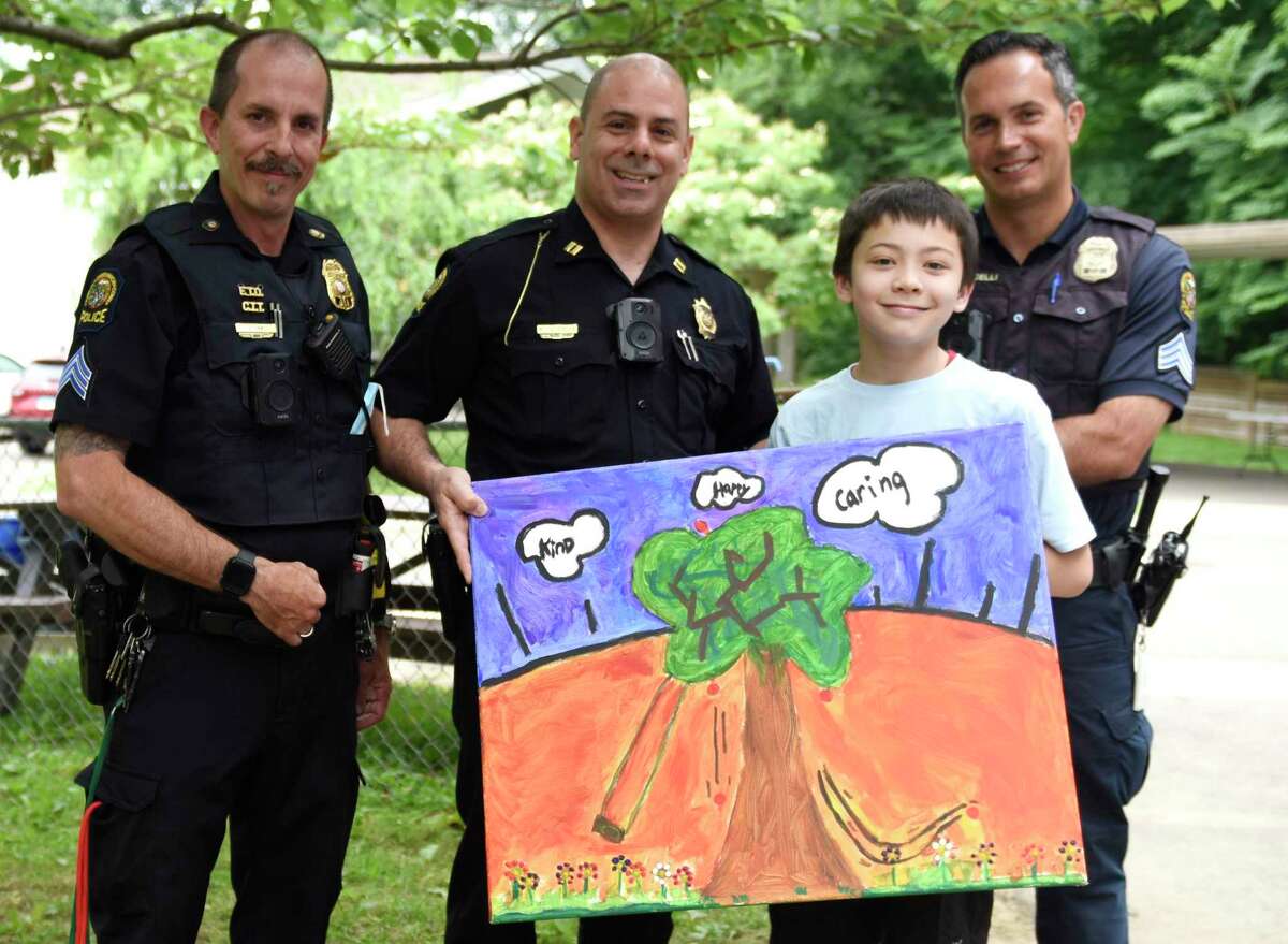 Fifth-grader Isaac Farr presents Greenwich Police officerJohn Tar, left, Police Captain Mark Zuccerella, center, and officer Pierangelo Carticelli with a painting for his Expression Through Art research project at International School at Dundee in the Riverside section of Greenwich, Conn. Tuesday, June 21, 2022. Farr's research project was on the theme of Art & Gratitude and created a painting for the Greenwich Police Department to express his gratitude through art.