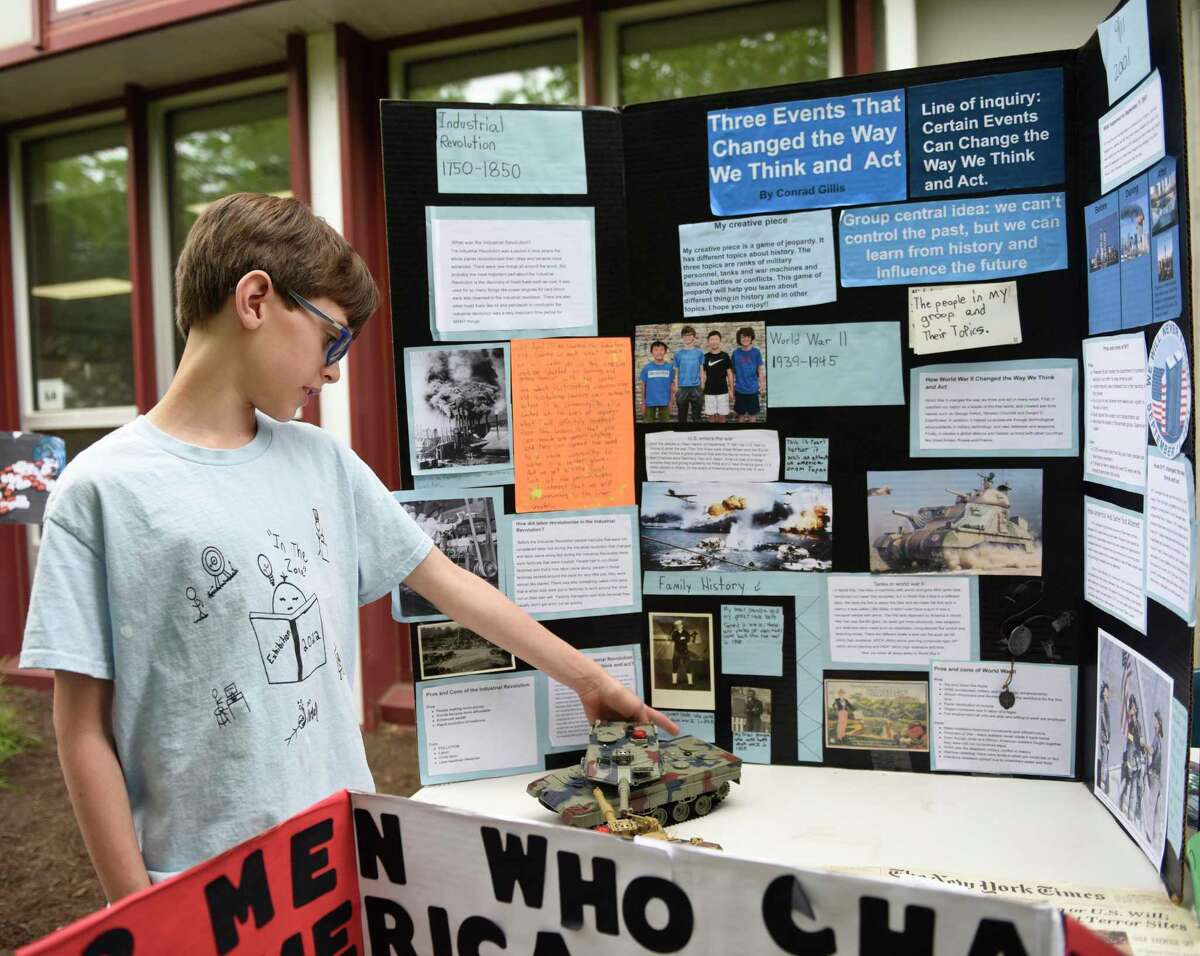 Conrad Gillis points to a photo of his family as he presents his research project at a fifth-grade exhibition 