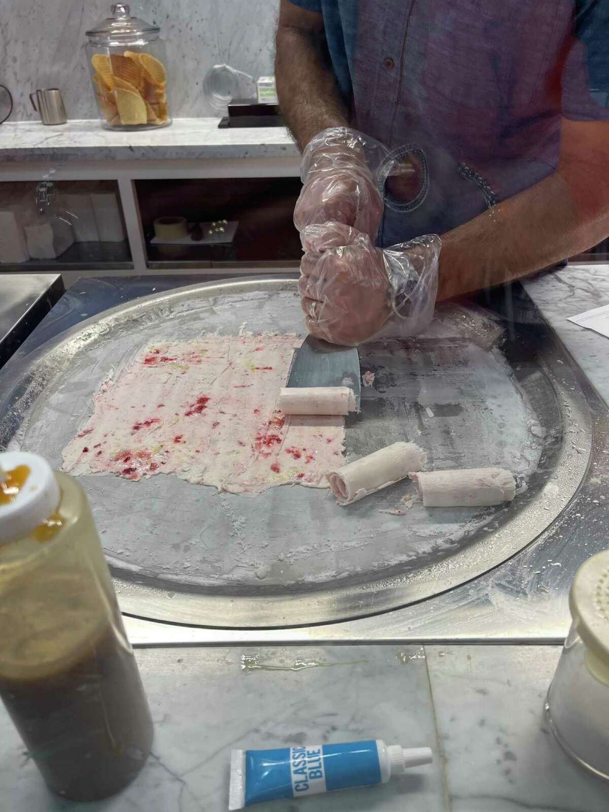 Michael Cordray turns liquid ice cream base into rolls of ice cream infused with banana and strawberries at the Galveston ice cream store he and his wife Ashley have opened.