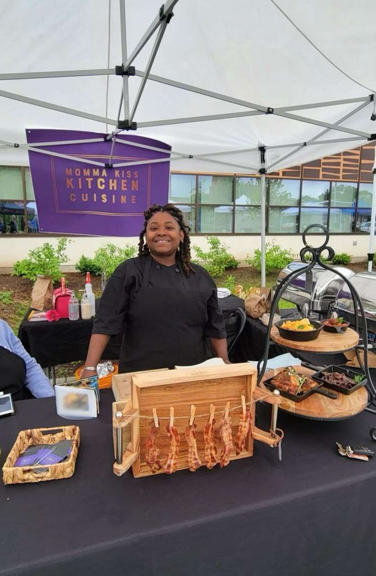 Kismet Douglass, proprietor of Momma Kiss Kitchen Cuisine, takes a quick break from work at the first-ever CitySeed Dixwell Community "Q" House Farmers Market on Wednesday, June 22, 2022.