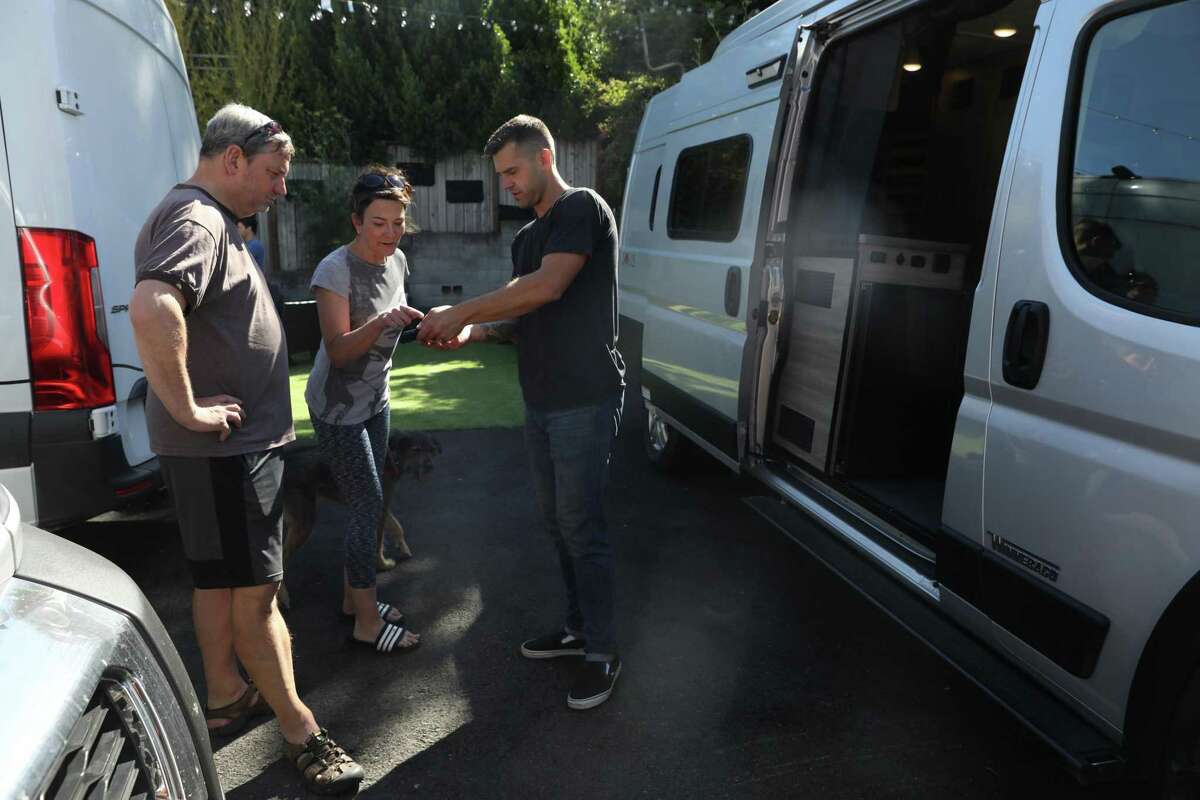 Jason Sibley-Liddle (right), owner of Simple Camper in Mill Valley, gets an e-signature from Sophie Fletcher before she and Keith Fletcher leave for a getaway in a camper van.
