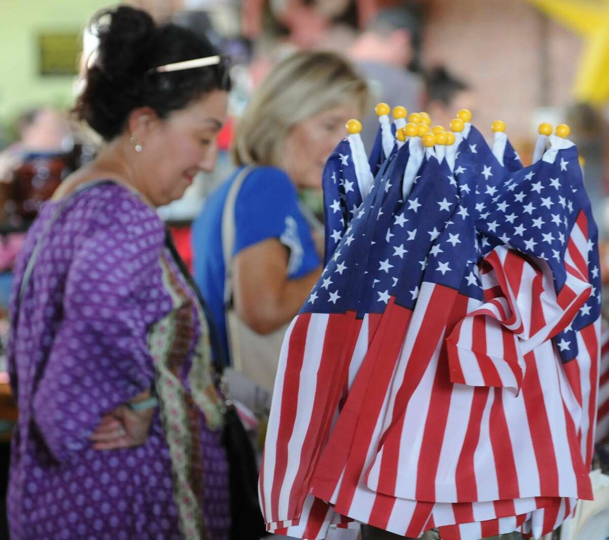 Visitors look over a collection of flags offered at The Riverside Flea Market in Grafton this weekend. The flea market is held the fourth weekend of every month from April through October. 