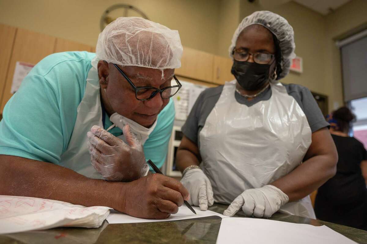 Food distributor Anthony Sutherlend and site manager Madeline Ferrell look over forms inside Bernice Fonteneau Senior Wellness Center in Washington on June 24, 2022. (