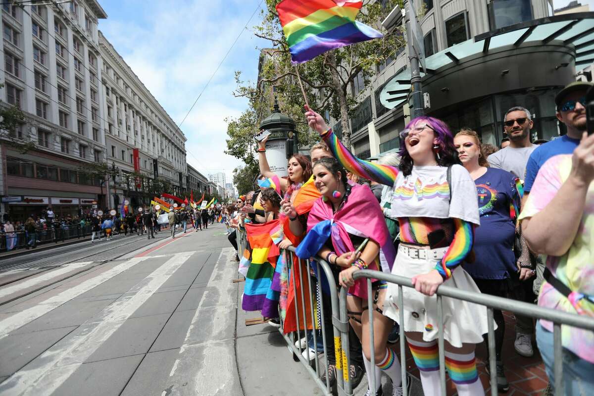 Attendees at San Francisco Pride watch the parade route down Market Street on June 26, 2022.