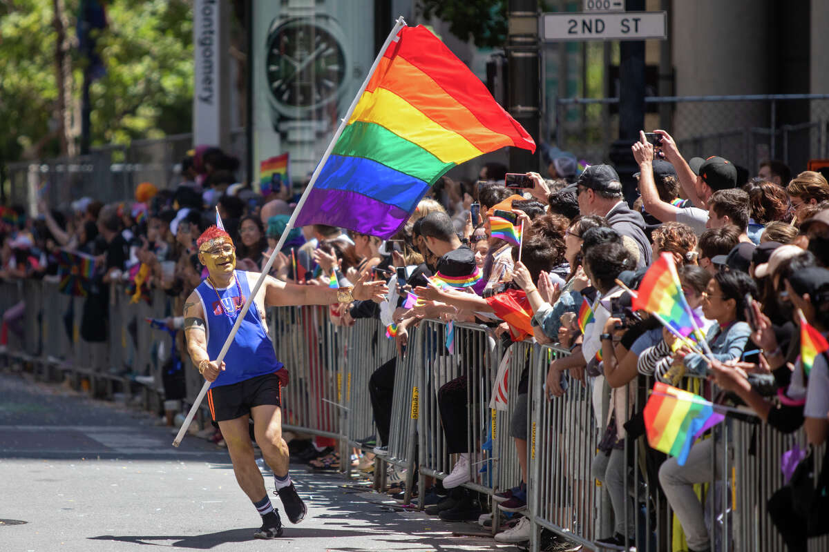 A participant carrying a rainbow flag hi-fives spectators during the San Francisco Pride parade in San Francisco, Calif.  on June 26, 2022.