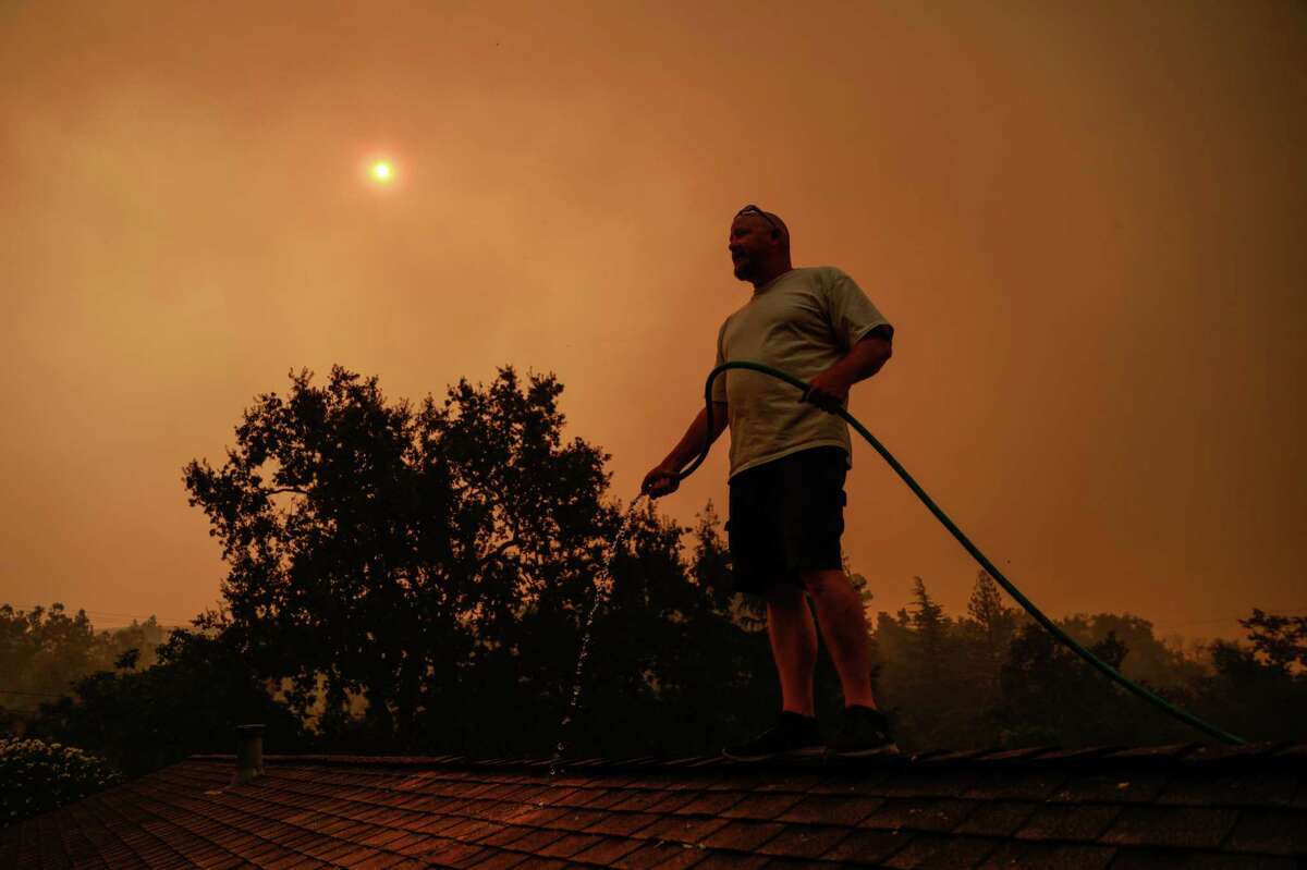 Tim Plowman waters down a friend’s home as he tries to save it from a wildfire before evacuating the LNU Lightning Complex fires in Vacaville in August 2020.