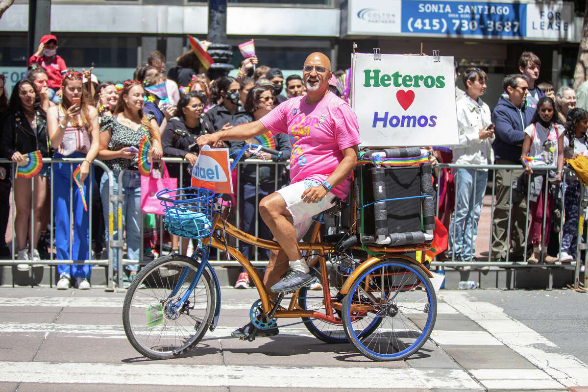 A person rides a bicycle with a sign attached during the San Francisco Pride Parade in San Francisco, California on June 26, 2022.
