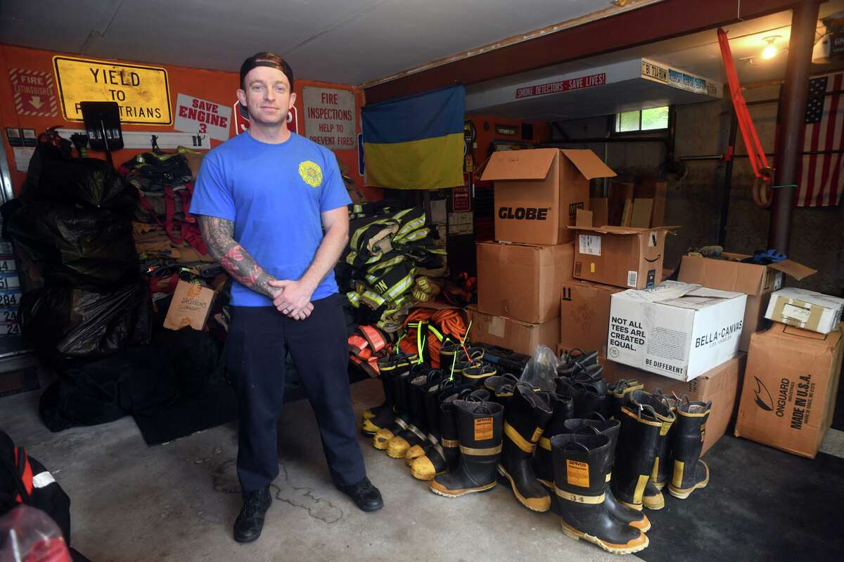 Fire Lt. Konstantin Tartakovsky poses in the garage of his Trumbull, Conn. home with firefighting equipment he has collected, June 23, 2022. A native of Ukraine, Tartakovsky is collecting the equipment and other supplies that will be shipped to Ukraine to assist relief efforts following the Russian invasion.