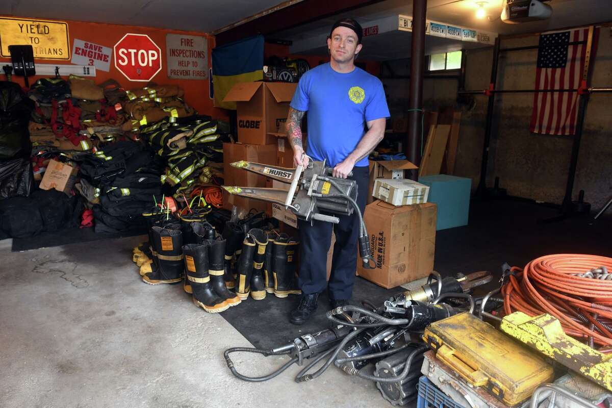 Fire Lt. Konstantin Tartakovsky poses in the garage of his Trumbull, Conn. home with firefighting equipment he has collected, June 23, 2022. A native of Ukraine, Tartakovsky is collecting the equipment and other supplies that will be shipped to Ukraine to assist relief efforts following the Russian invasion.