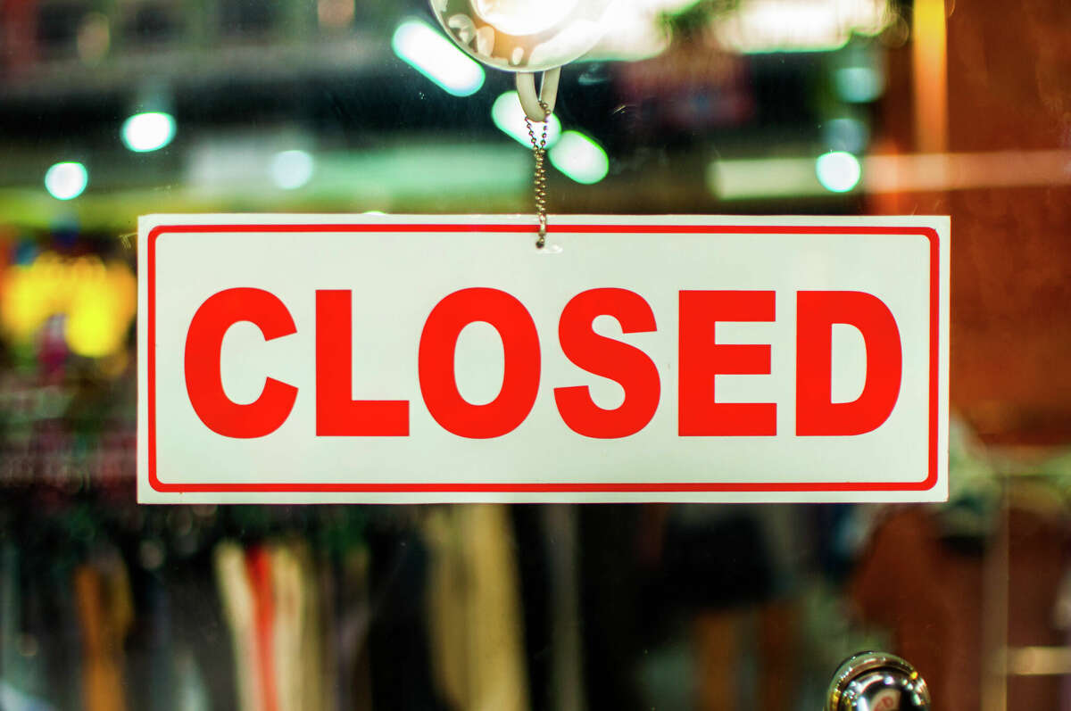 A glass door with red and white "closed" store sign