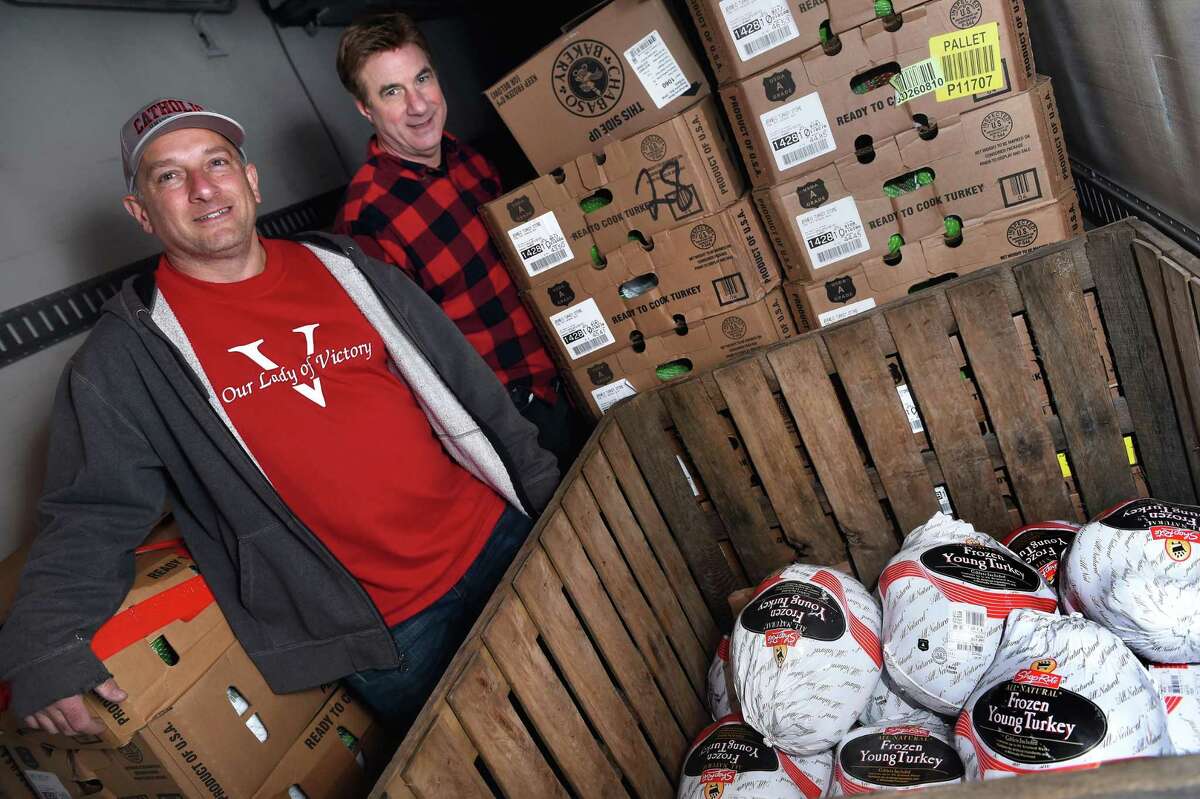 In this Nov. 22, 2021, photo, Our Lady of Victory Church Deacon Dean Macchio, left, and Vertical Church Senior Pastor Ken Vance stand inside a refrigerated truck where the last of some 2,000 turkeys remain for distribution outside of the Vertical Church in West Haven.