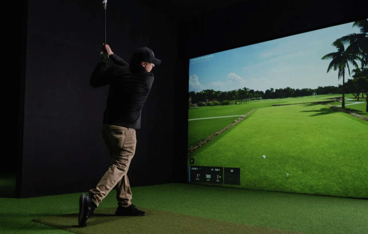 A golfer swings on one of Back 9 Social's virtual golf bays.