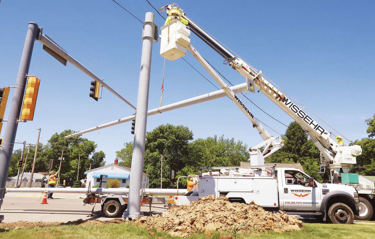 John Badman|The Telegraph Workers from Wissehr Electric Inc. in Belleville work Monday at the intersection of Godfrey Road and Celesta Street in Godfrey to install new overhead traffic arms and lights. The work is part of an ongoing project to replace traffic light systems that are aging in the Metro East. The old light pole, arm and lights, left, will be removed when the new ones are wired. Last week the lights and overhead arm were replace at the Stamper Lane intersection.