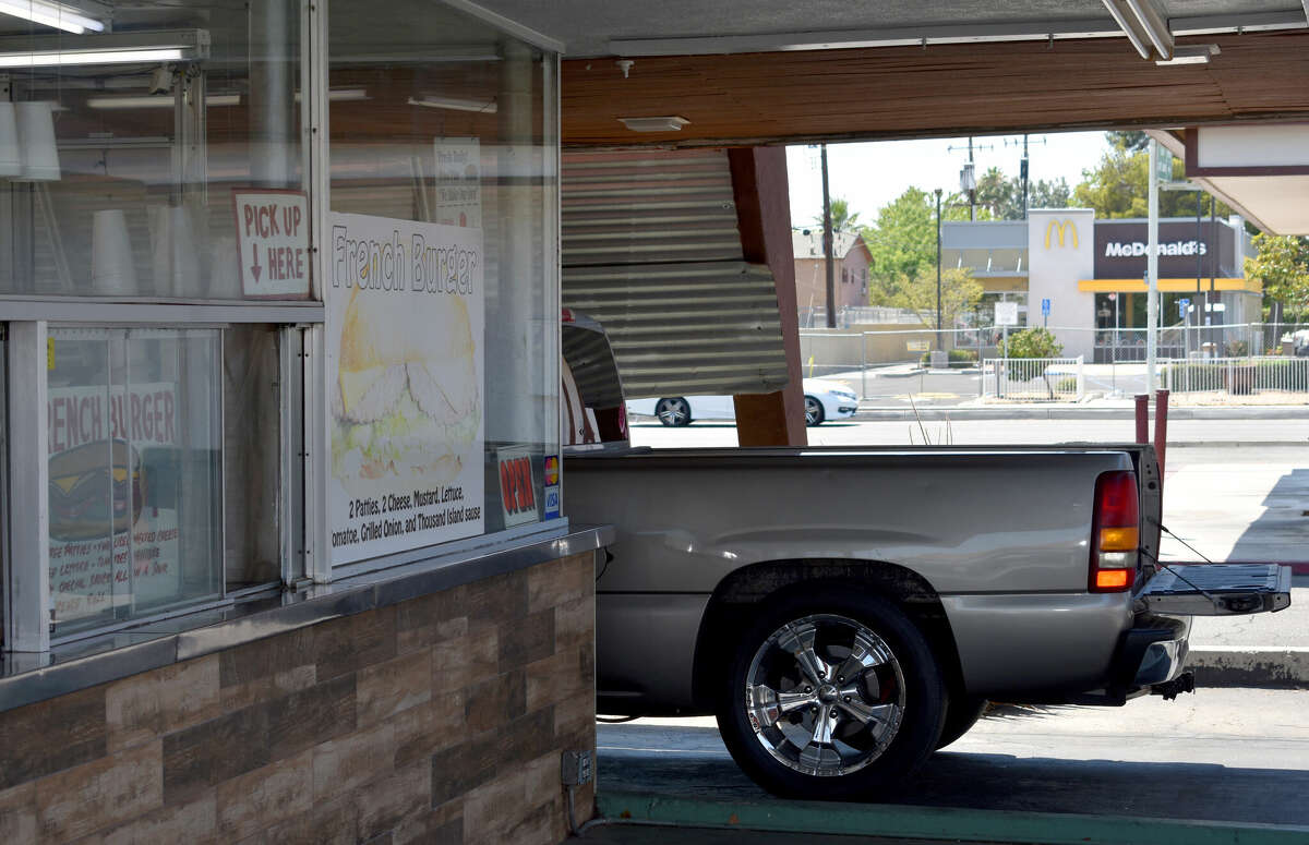 As a passenger in a pick-up waits for their meal at Andre's Drive-In in Bakersfield, a McDonald's looms in the background. The McDonald brothers originally offered the Andre family one of the first of their burger franchises.