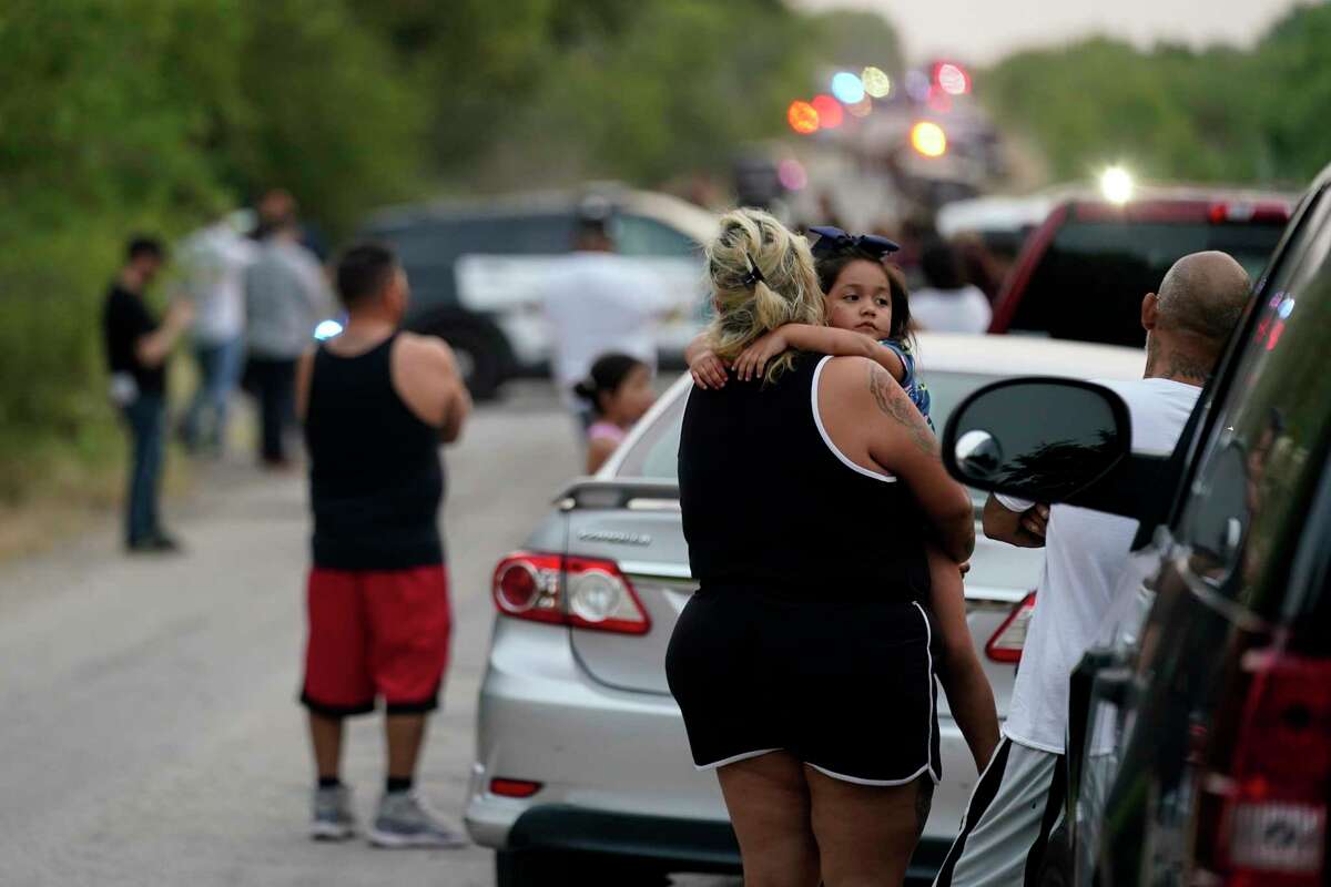 Onlookers stand near the scene where a tractor trailer with multiple dead bodies was discovered, Monday, June 27, 2022, in San Antonio. (AP Photo/Eric Gay)