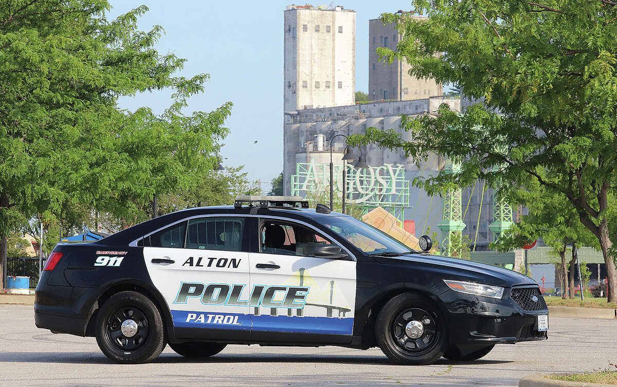 John Badman|The Telegraph An Alton Police officer sits in his car still guarding the scene Tuesday where two people were shot just before 1 a.m. Tuesday. Alton firefighters washed down the scene with a hose about 8 a.m. Tuesday. 