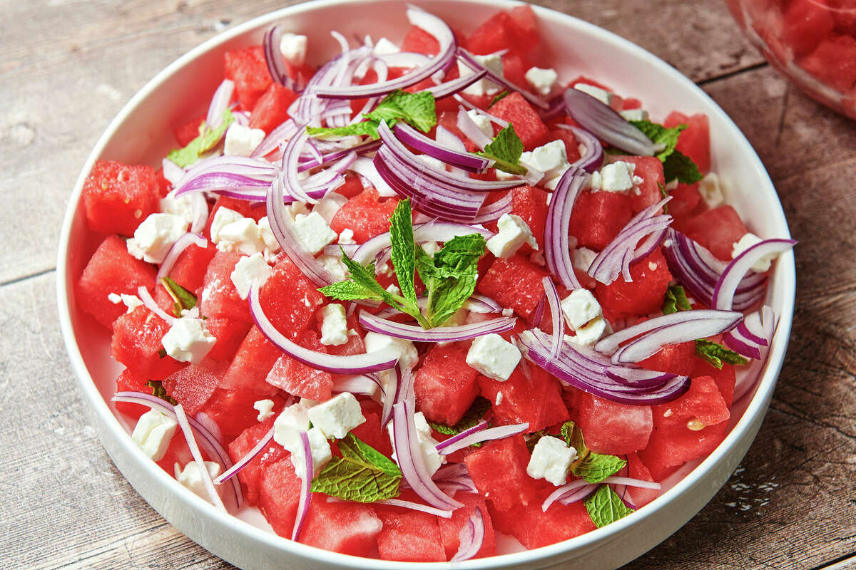 Watermelon-Feta Salad is topped with thinly sliced red onion and mint leaves.