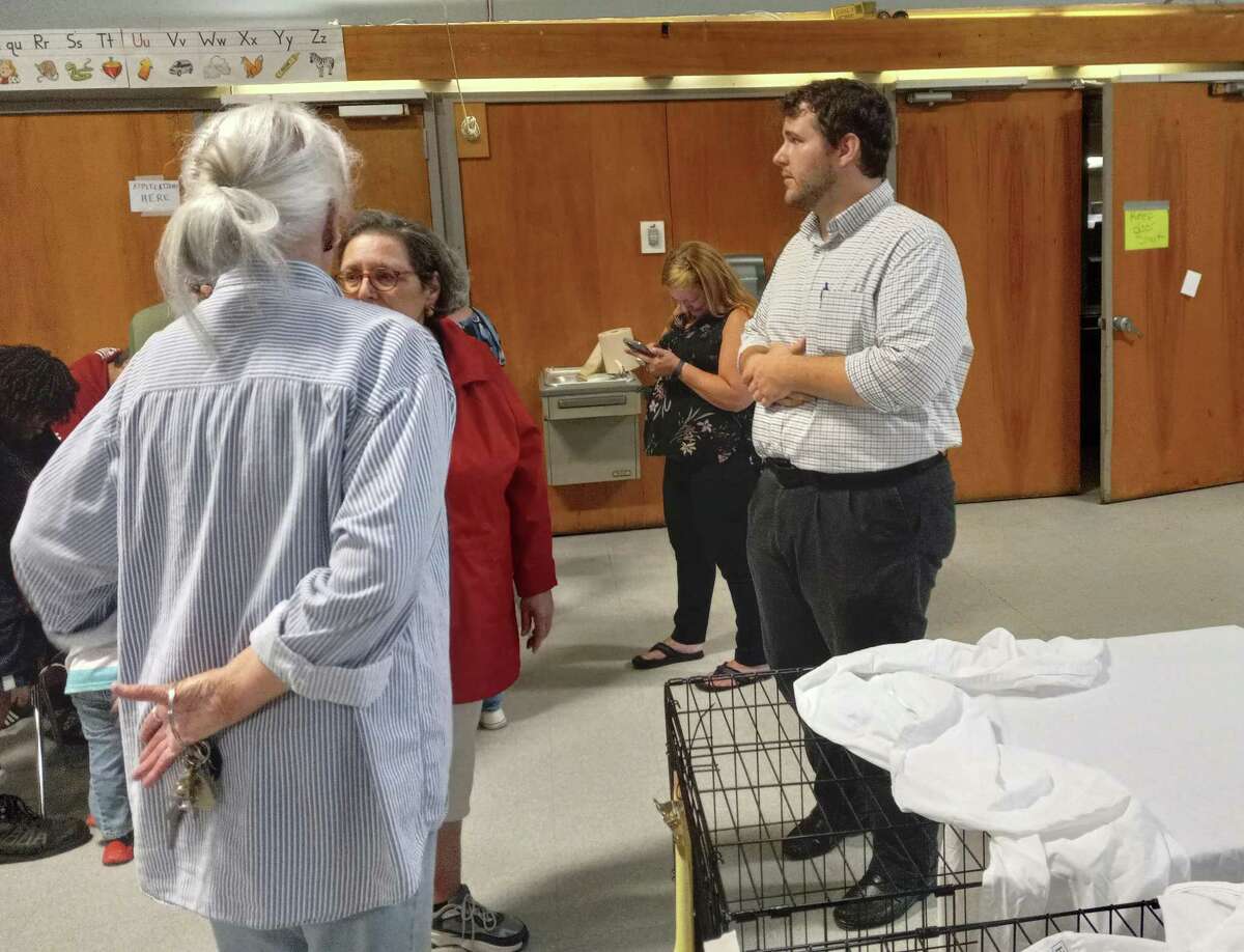 Town Manager Josh Kelly, right, speaks with a resident during an adoption night at the Batcheller School, where a temporary shelter has been set up to care for cats taken from a hoarding situation in Winsted. Many were taken to shelters across the state.