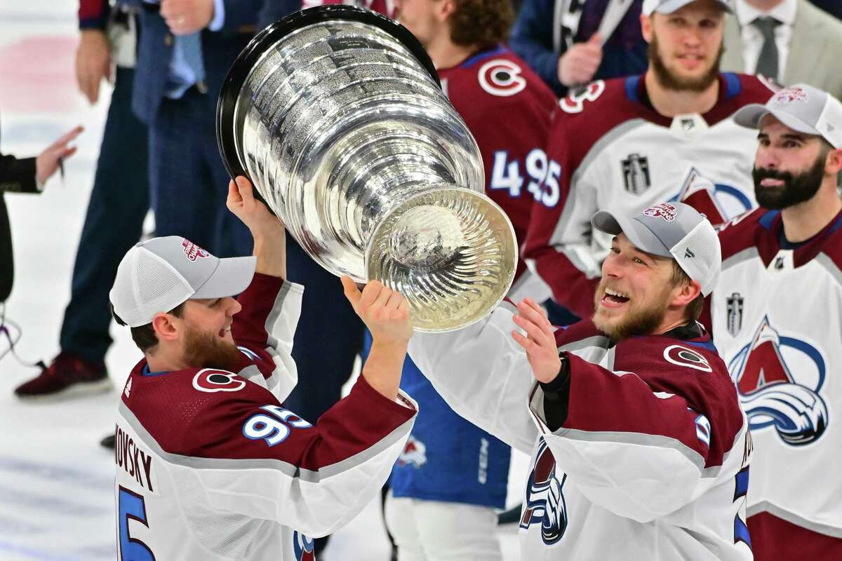 Accepting the Stanley Cup from teammate Andre Burakovsky, Avalanche goalie Darcy Kuemper (right) became the latest ex-Houston Aero to win hockey's holy grail.