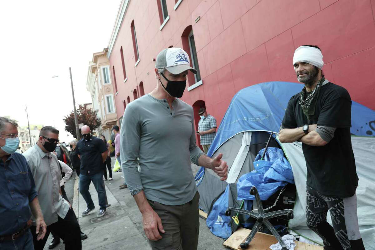 Gov. Gavin Newsom visits with Ariel Fortuna at a homeless encampment on 19th Street in San Francisco on Aug. 27, 2021. Newsom supports a bill that would create Care Courts to get those with severe mental illness into treatment and off the streets.