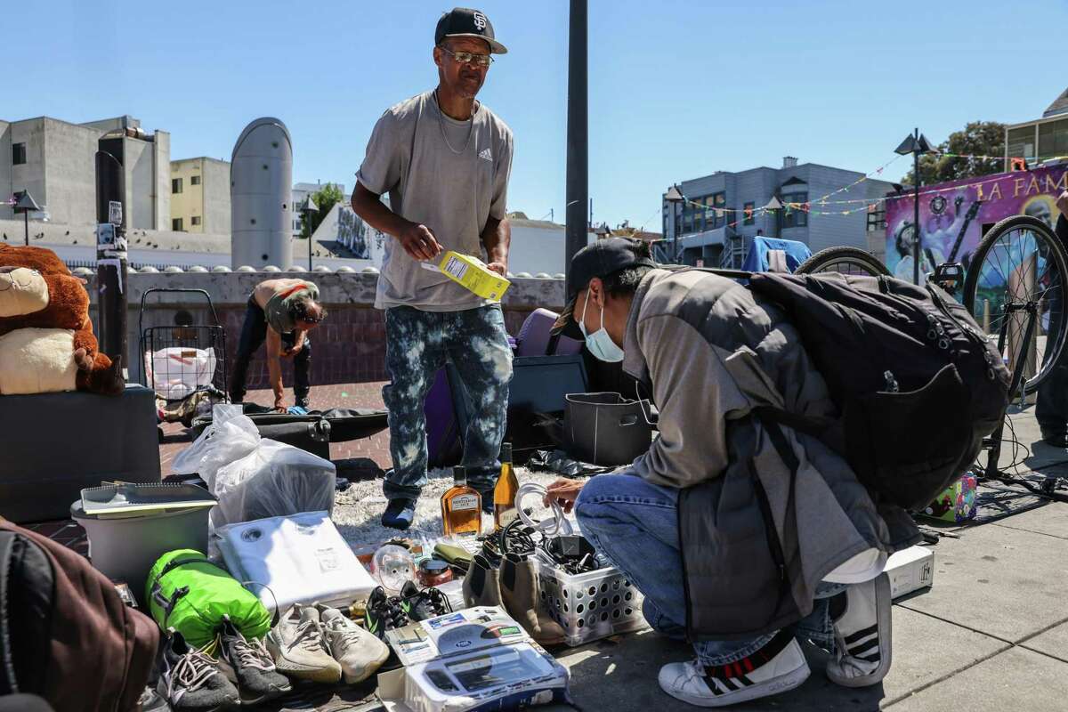 Rome Allen (left) helps a customer as he shops for items on 24th Street in San Francisco.