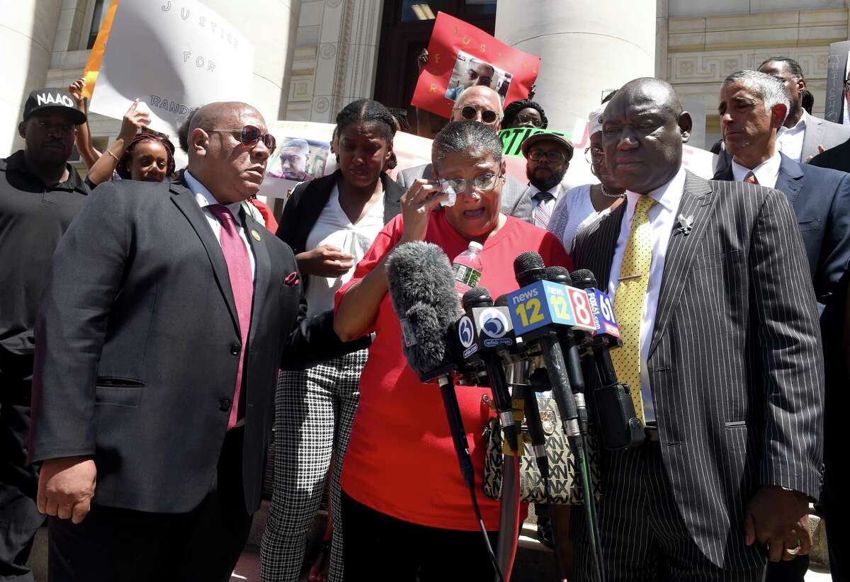 Scot X. Esdaile, left, president of the Connecticut NAACP, and civil rights attorney Benjamin Crump, right, listen to Doreen Coleman, center, mother of Richard “Randy” Cox Jr., speak on the steps of Superior Court in New Haven Tuesday at a news conference concerning the injuries sustained by Cox while being transported in a New Haven police van.