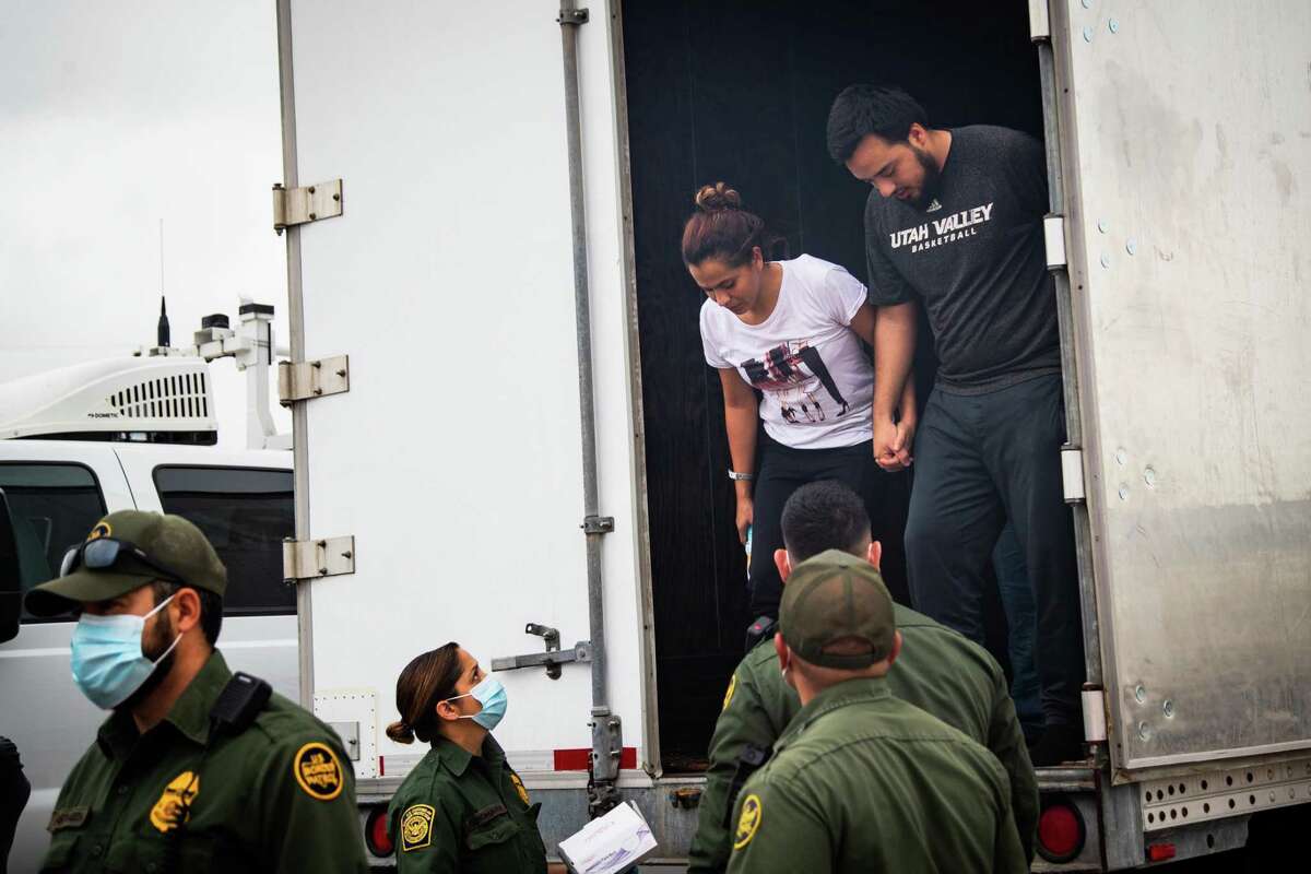 Two people holdings hands exit a cargo trailer as they are processed after being found with several dozen other people inside a trailer at a U.S. Customs and Border Protection inspection station at Interstate 35, are mobilized to be processed, Wednesday, May 26, 2021, in Laredo. The group are suspected of crossing the U.S./Mexico border unauthorized.