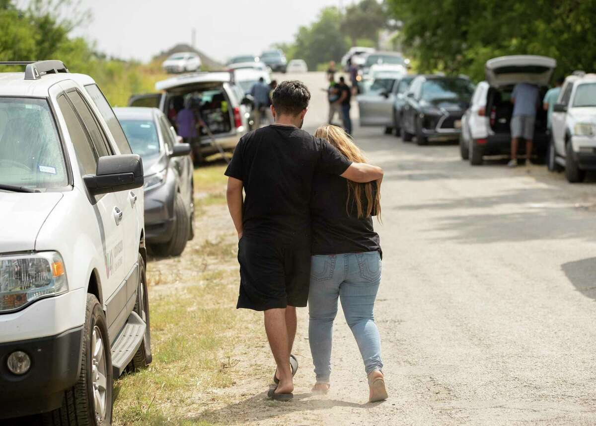 Dynasty Chavez and Cesar Mendiola walk away after looking at the scene Tuesday, June 28, 2022, in San Antonio where dozens of migrants were found dead in a tractor-trailer on Monday after being abandoned in the sweltering heat. It's the latest tragedy to claim the lives of migrants smuggled across the border from Mexico to the U.S. (Jay Janner /Austin American-Statesman via AP)