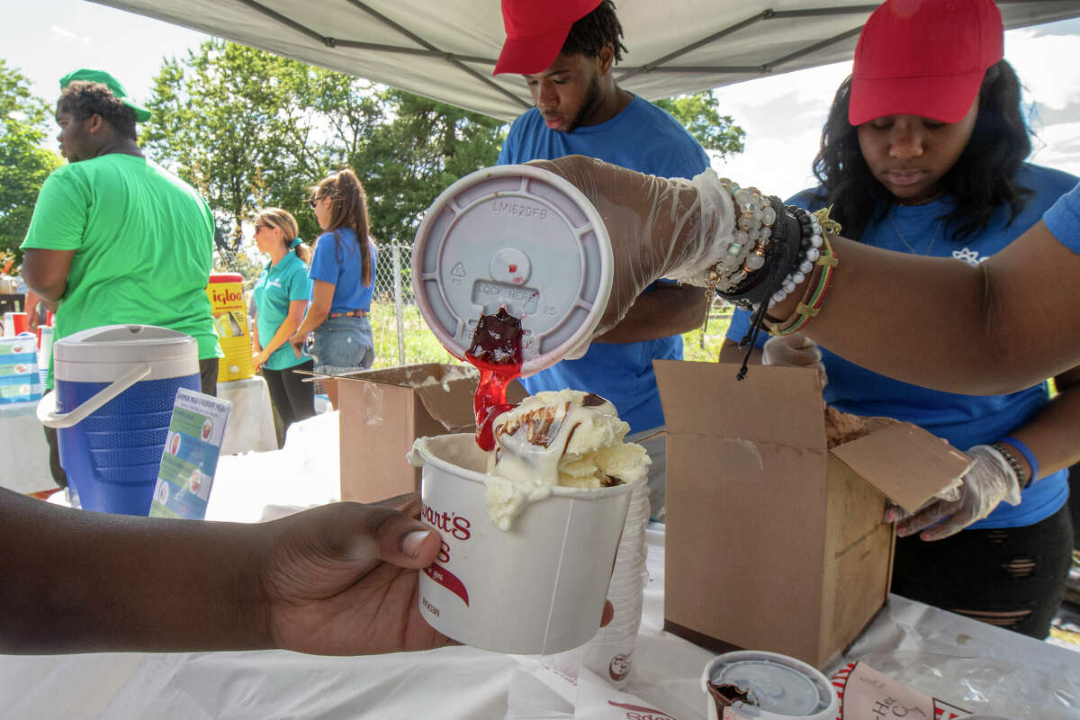 A volunteer makes an ice cream sundae at a kickoff party where kids are fed free lunches and free ice cream sundaes hosted by the Schenectady Inner City Ministry at Vale Farm Park on Tuesday, June 28, in Schenectady, N.Y. SICM got a grant to feed kids free lunches thru the summer at dozens of locations including this community farm. (Lori Van Buren/Times Union)
