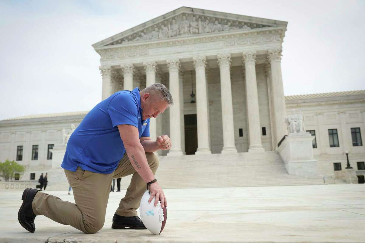 In this photo from April 25, 2022, former Bremerton High School assistant football coach Joe Kennedy takes a knee in front of the U.S. Supreme Court after his legal case, Kennedy vs. Bremerton School District, was argued before the court in Washington, DC. Kennedy was terminated from his job by Bremerton public school officials in 2015 after refusing to stop his on-field prayers after football games. (Win McNamee/Getty Images/TNS)