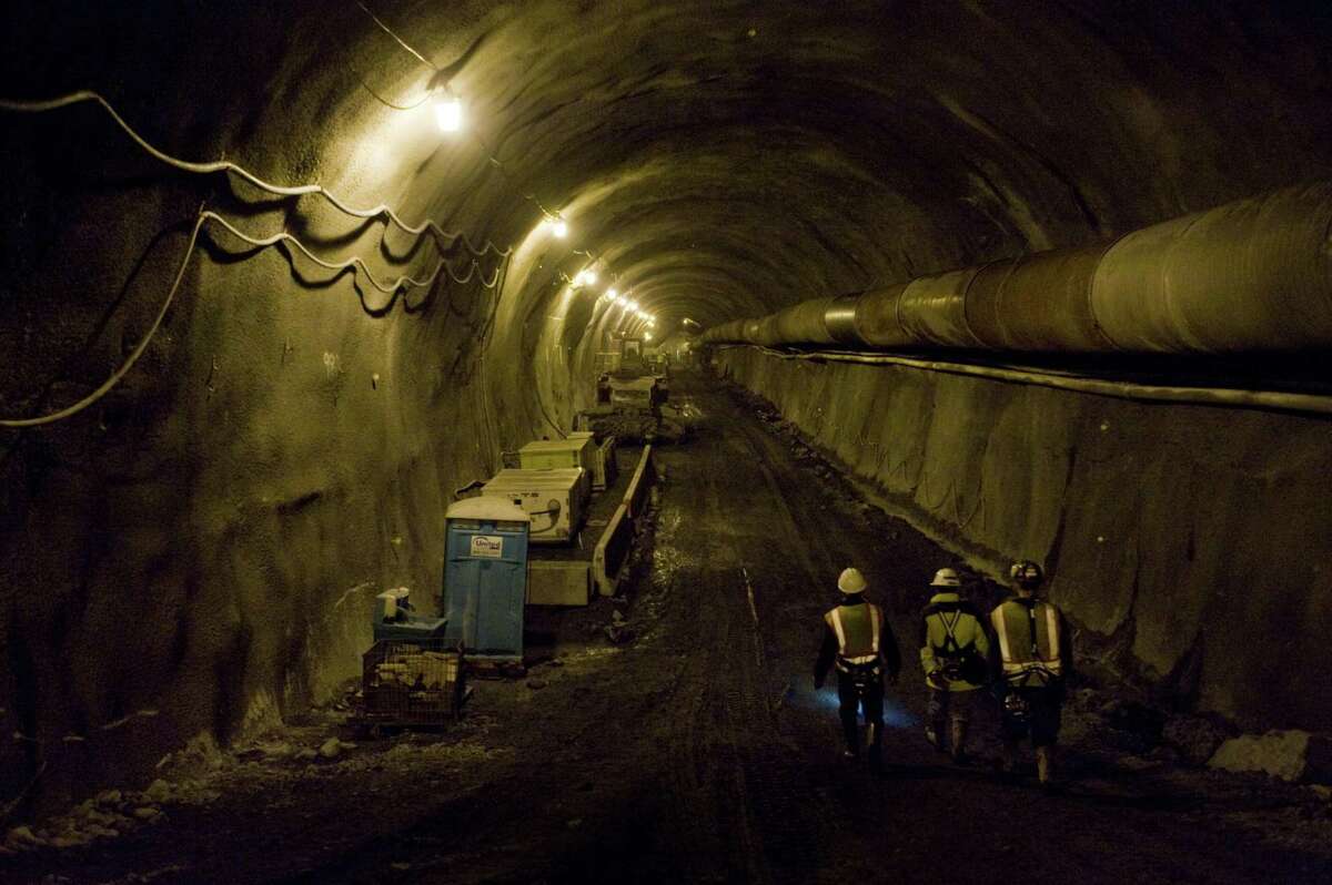 Caltrans workers and media personnel walk the approximately 4,200 feet of completed tunnel at the Devil’s Slide Bypass in June 2010. The Tom Lantos Tunnels opened to the public in 2013.