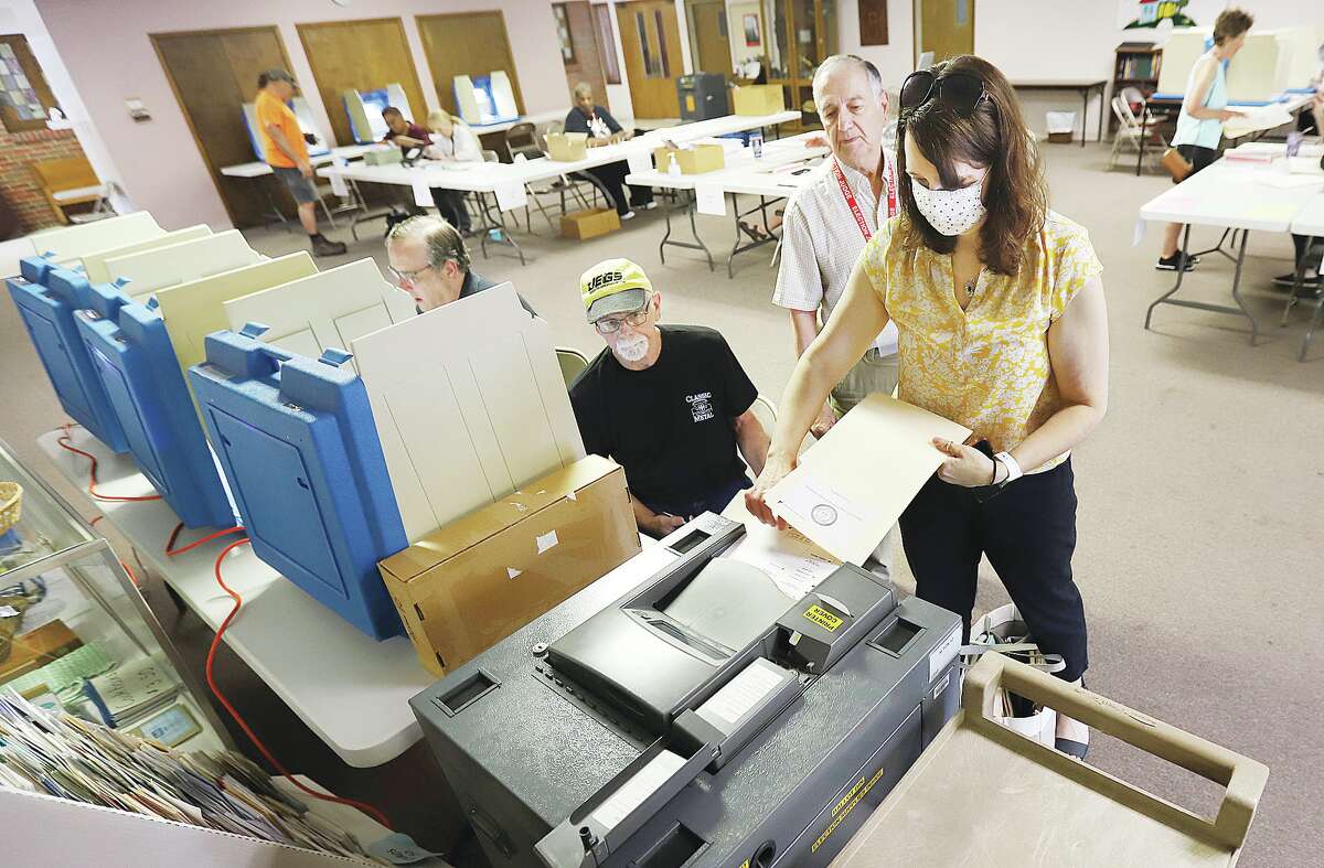 John Badman|The Telegraph A woman casts her vote in Alton Precinct 10 Tuesday at Messiah Lutheran Church on Milton Road as election judge John Siampos, center, supervises. Voter turnout was fairly light early Tuesday.