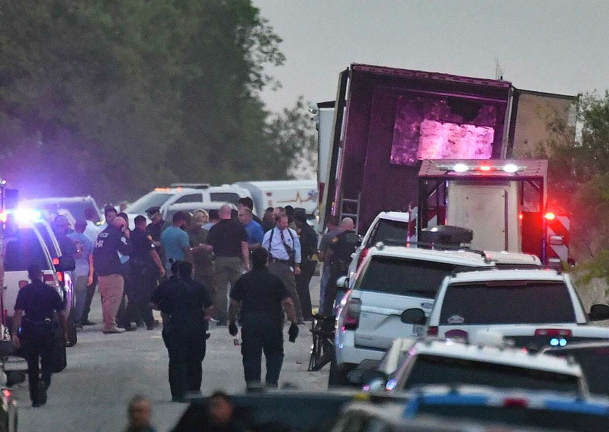 Emergency personnel survey the scene where roughly 100 migrants — 53 of whom have died — were found trapped in a semitrailer on the Southwest Side on Monday.