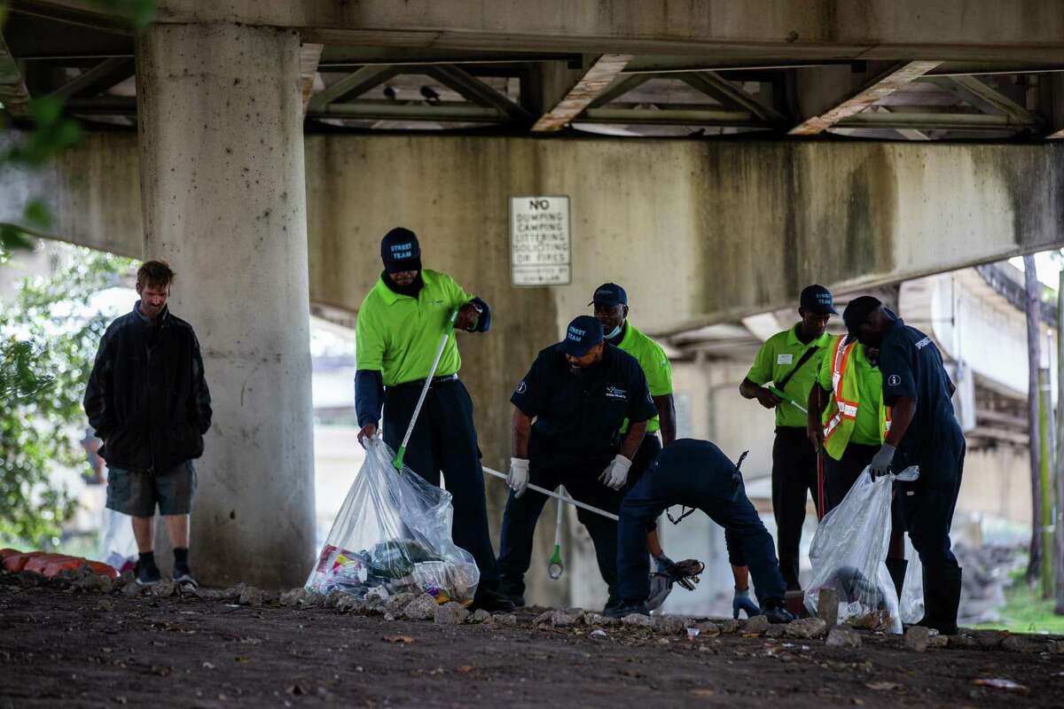 Downtown District’s cleaning crew clears trash from under I-45 where tents set up by unhoused people were located before getting set up in apartments, Tuesday, Nov. 16, 2021, in Houston.