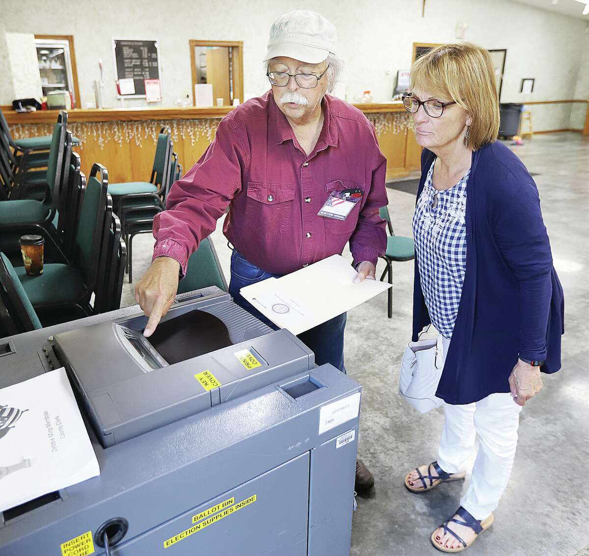 Inside the Godfrey Knights of Columbus, 1713 Stamper Lane, Godfrey, election judge Clement Williams, left, helps a voter cast her ballot in Godfrey Precinct 2 in a previous election.