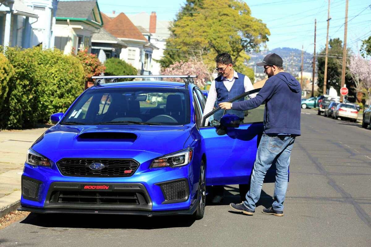 Tyler Karon (right) rents David Chu’s car in Alameda in 2018, a transaction conducted through the company Turo. A state appeals court ruling allows Turo to avoid an airport permit fee.