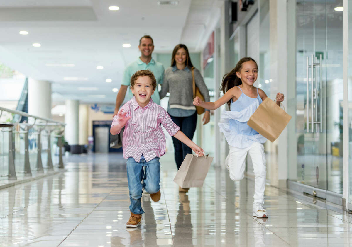 Happy Latin American family shopping and running towards the camera at the mall - lifestyle concepts