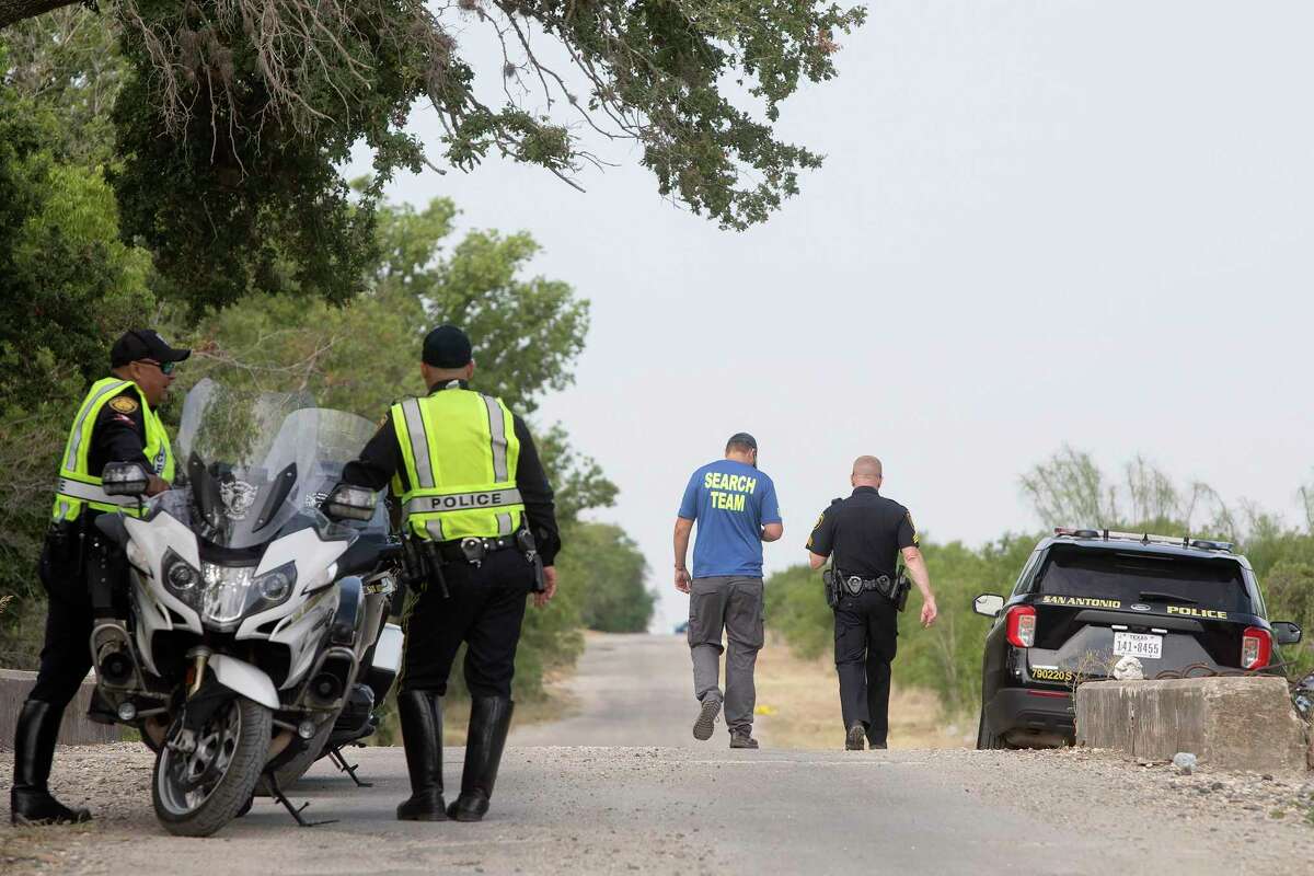 Police and a search team member on June 28, 2022, at the place where dozens of migrants were found dead in and around a tractor-trailer the day before, in San Antonio, Texas. The trailer passed through a federal immigration checkpoint inside the U.S. without being inspected, according to a top Mexican official. (Lisa Krantz/The New York Times)