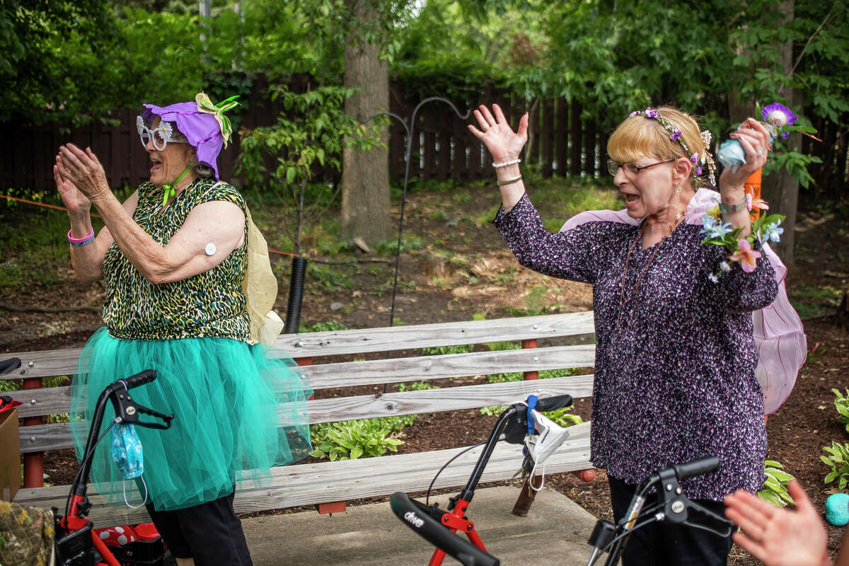Lucy McVey, left, and Ina Zebrak, right, clap for a child after he scores during a ring toss game as community members join residents of Washington Woods senior housing for a Fairy Garden celebration Thursday, June 30, 2022 in Midland.