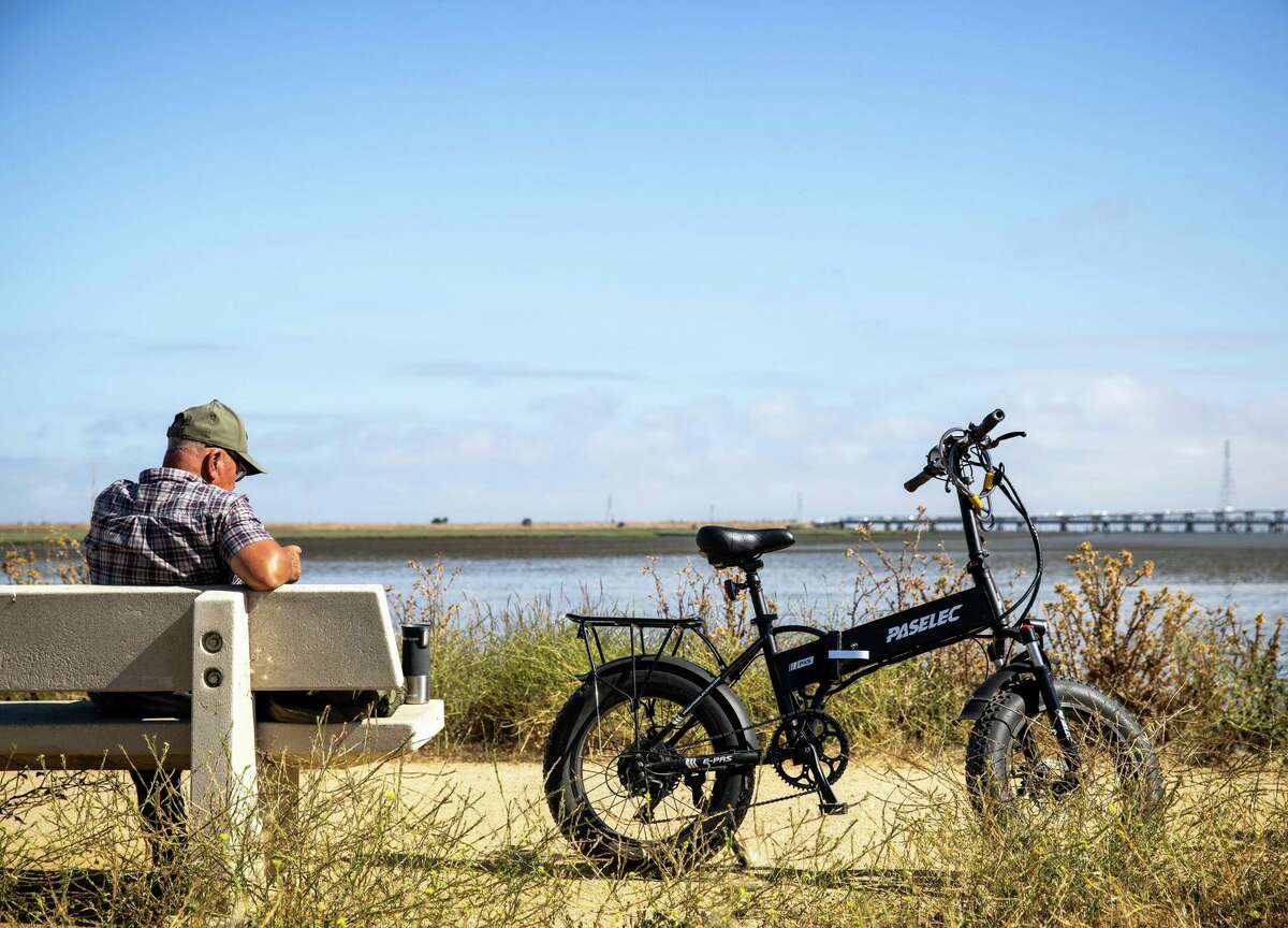Refugio Flores rests on a bench next to his electric bike at the Ravenswood Preserve in East Palo Alto.