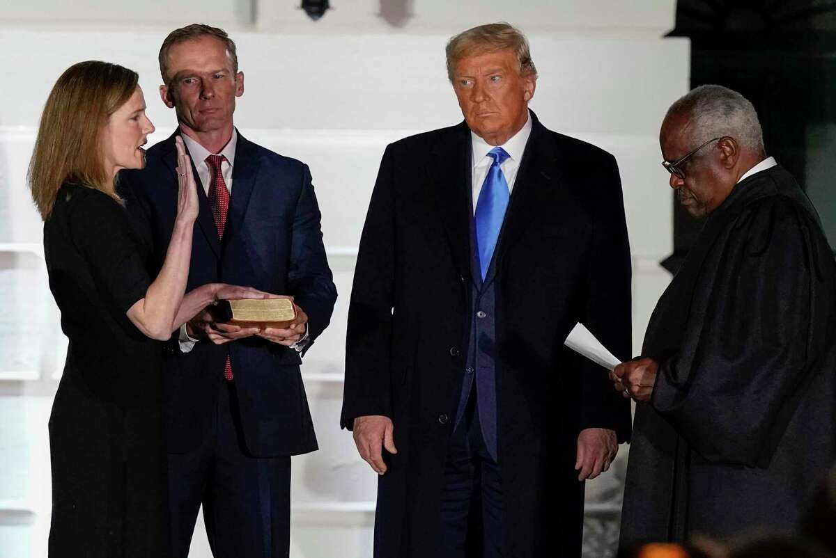 FILE - President Donald Trump watches as Supreme Court Justice Clarence Thomas administers the Constitutional Oath to Amy Coney Barrett on the South Lawn of the White House White House in Washington, Oct. 26, 2020. Holding the Bible is Barrett's husband, Jesse Barrett. Eight of the last nine Republican nominees to be confirmed to the Supreme Court, from the Reagan to the Trump presidencies, have had Catholic pedigrees including Barrett. (AP Photo/Alex Brandon, File)