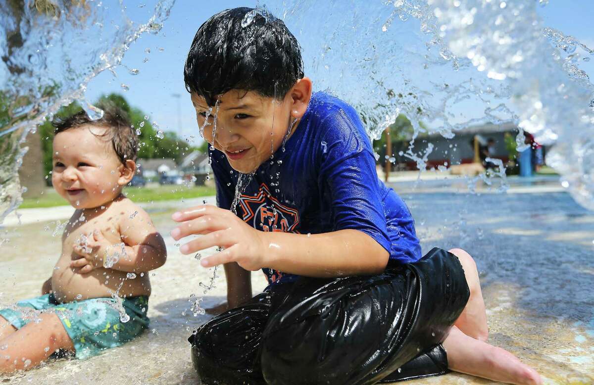 Isaiah Luviano, 8, and his 11-month-old brother Noah keep cool under a water feature at Montie Beach Park last month. June 2022 was the hottest June on record in Houston.