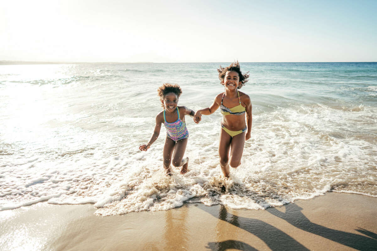 Happy children run along the beach.