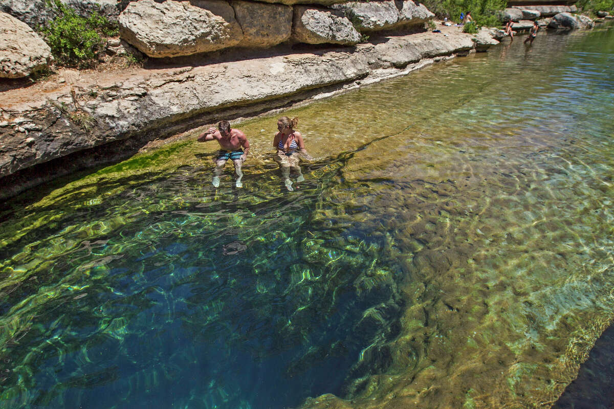 Art Larson, left, and Courtney Crockett sit on the edge of the Hays County's Jacob's Well Natural Area in Wimberley, Texas, on Wednesday, April 30, 2014.
