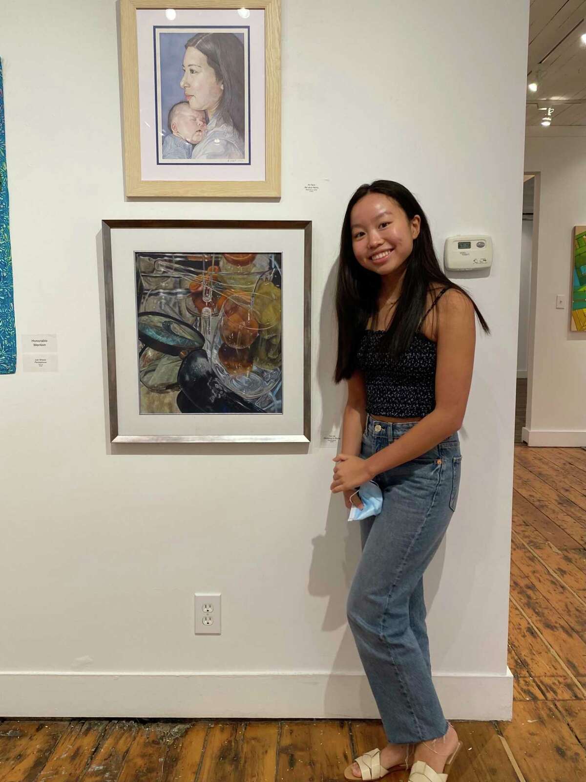 Ava Lee, 17, stands by her art at the Ridgefield Guild of Artists Sept. 10, 2021. Her latest exhibit, on display at the Greenwich Arts Society, shows pieces of her journey with scoliosis.
