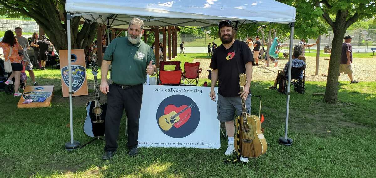 New Milford resident Vincent Rodriguez has started a nonprofit, Smiles I Can't See, that gives away guitars to children. He is pictured on the right with New Milford Mayor Pete Bass on the left.