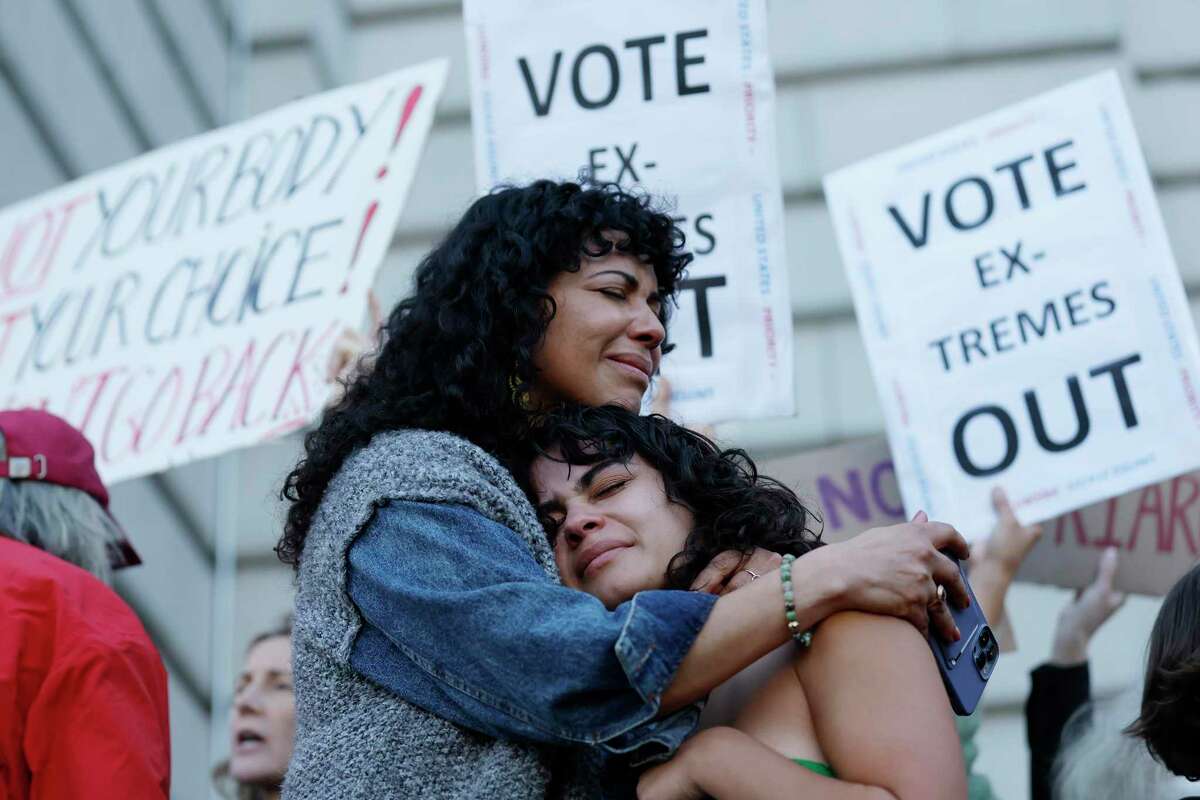 6月24日，最高法院决定推翻罗伊诉韦德案后，米齐·里瓦斯(左)在旧金山市政厅举行的堕胎权利集会上拥抱她的女儿玛雅·伊里巴伦。法院决定终止宪法对堕胎的保护，可能会导致更多已经面临医疗不平等的黑人女性死亡。